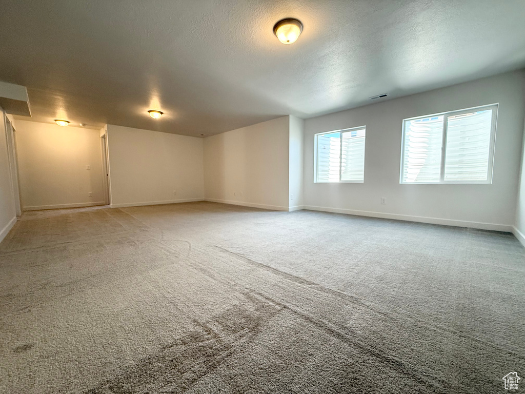 Unfurnished room featuring baseboards, a textured ceiling, and carpet floors