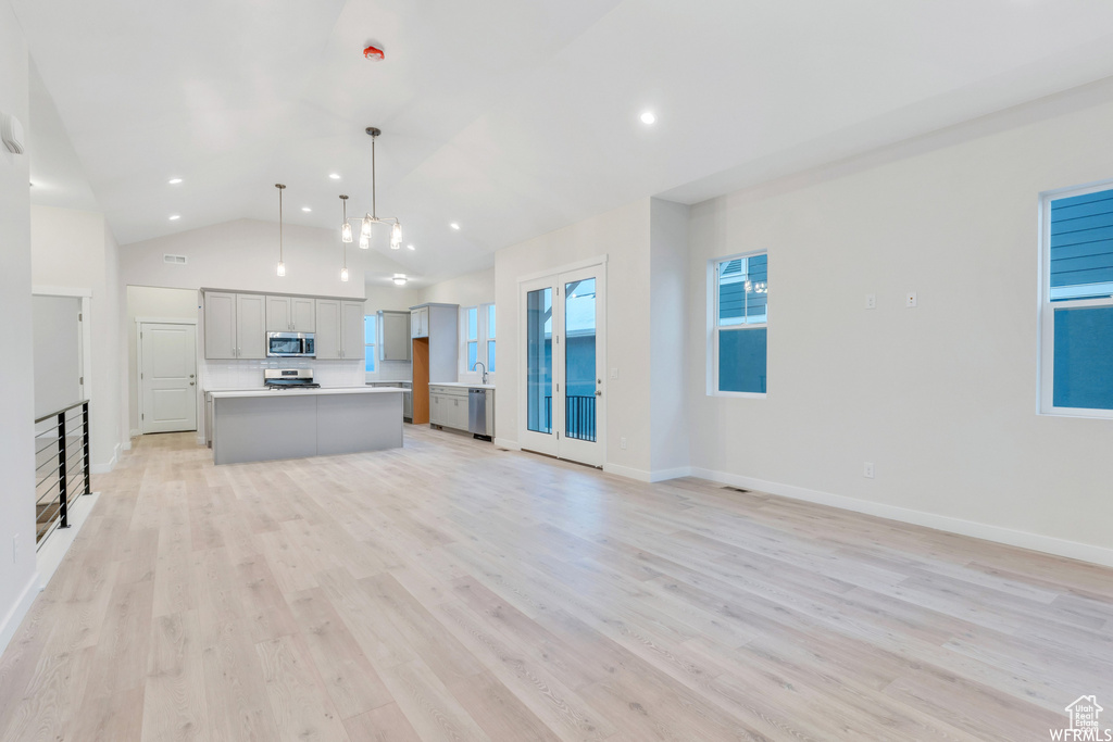 Unfurnished living room with light wood-type flooring, high vaulted ceiling, baseboards, and recessed lighting