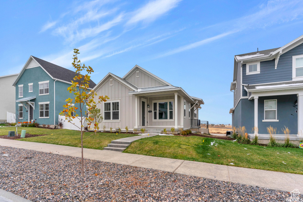 View of front of property featuring covered porch, board and batten siding, and a front yard