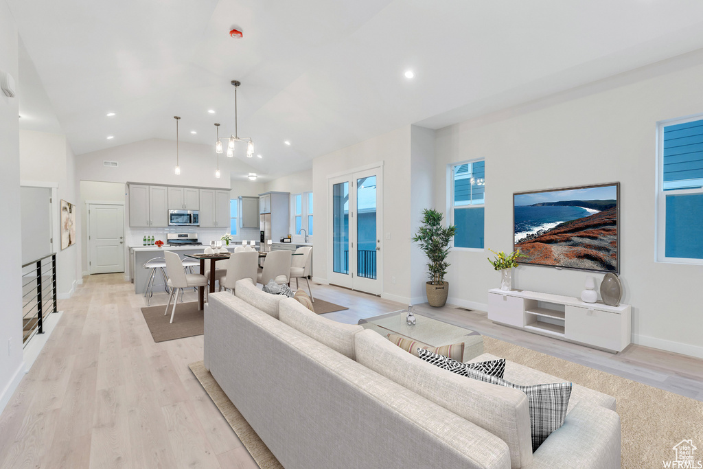Living area with baseboards, light wood-style floors, recessed lighting, and high vaulted ceiling