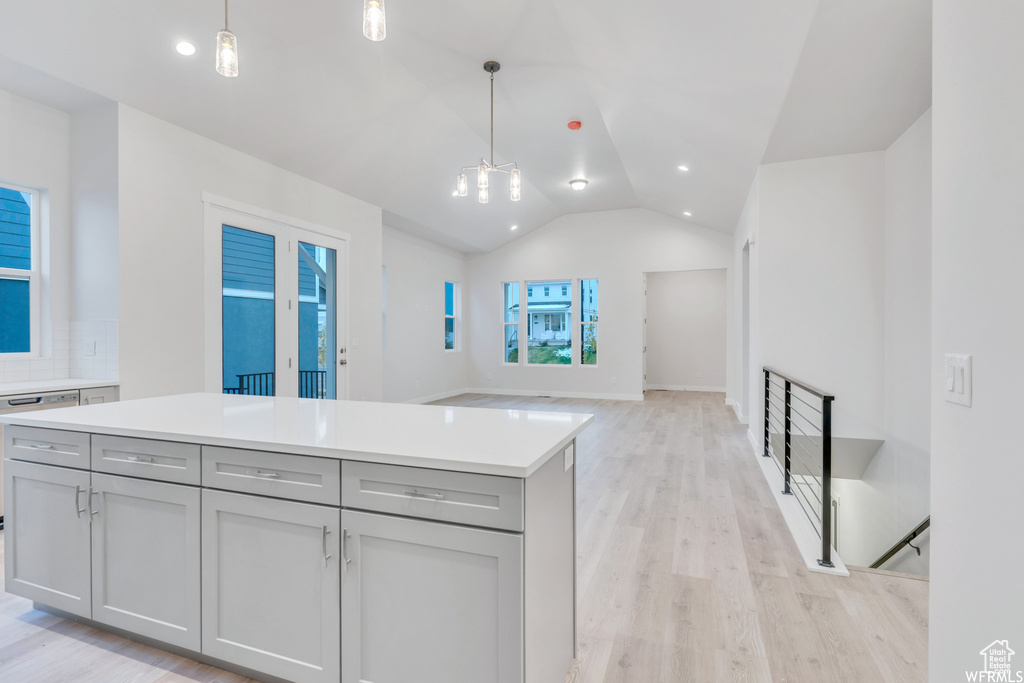 Kitchen with light wood finished floors, gray cabinets, lofted ceiling, and pendant lighting