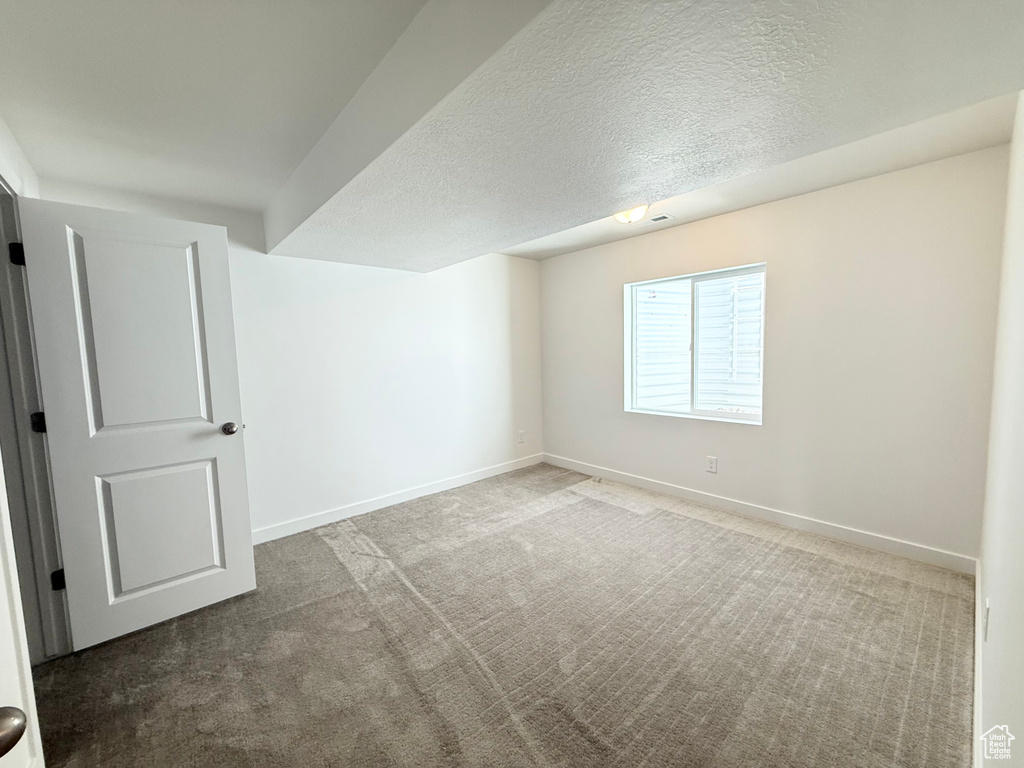 Below grade area featuring carpet, a textured ceiling, and baseboards