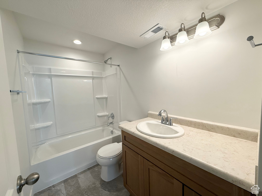 Bathroom with toilet, stone finish flooring, visible vents, shower / tub combination, and vanity