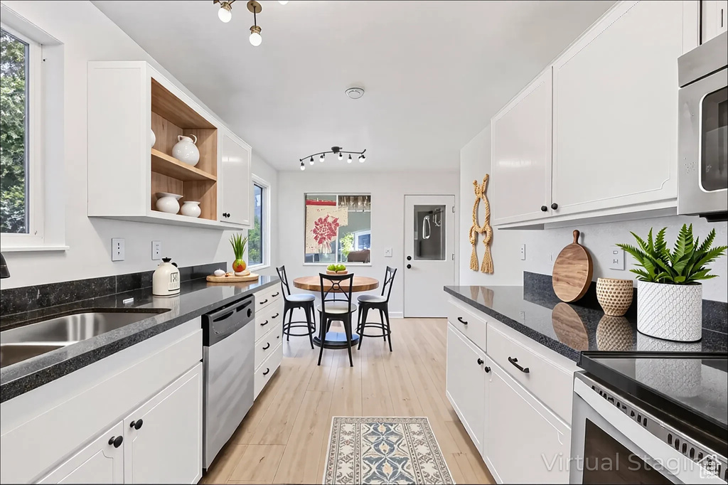 Kitchen featuring stainless steel appliances, light wood-style flooring, open shelves, white cabinetry, and dark stone counters
