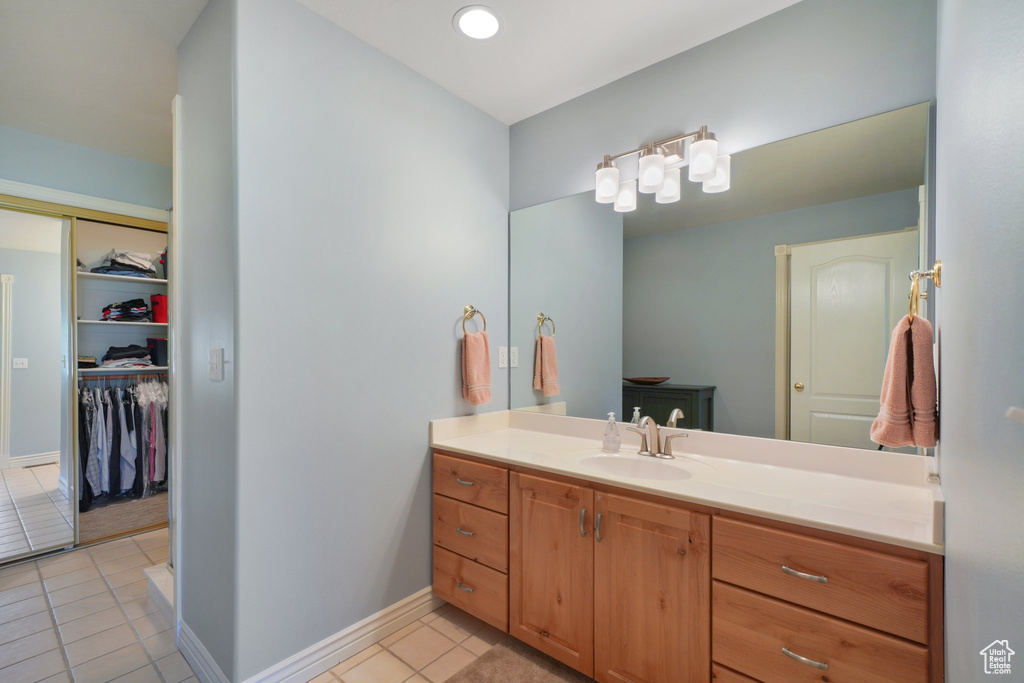 Bathroom with tile patterned flooring, baseboards, a spacious closet, and vanity
