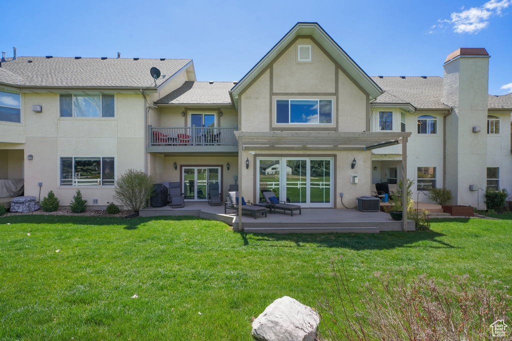 Rear view of house with a patio, a yard, stucco siding, and a balcony