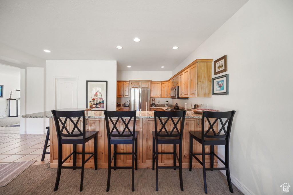 Kitchen featuring recessed lighting, appliances with stainless steel finishes, light stone countertops, and a peninsula