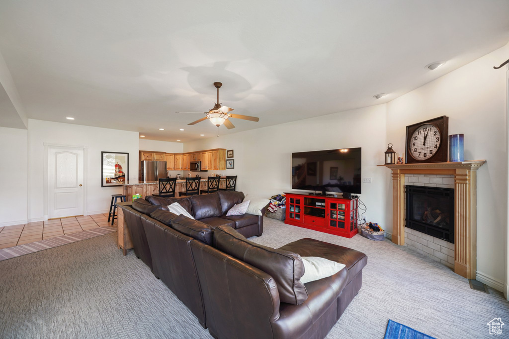 Living room with a glass covered fireplace, ceiling fan, light carpet, and recessed lighting