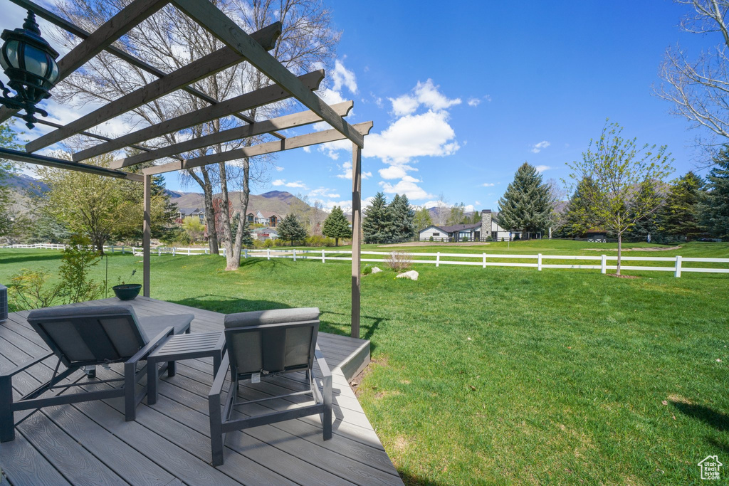 Deck featuring fence, a yard, a pergola, and a mountain view