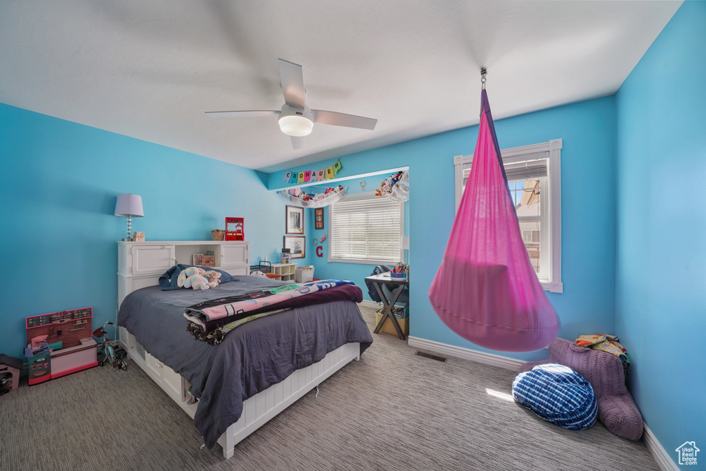 Carpeted bedroom featuring visible vents, a ceiling fan, and baseboards