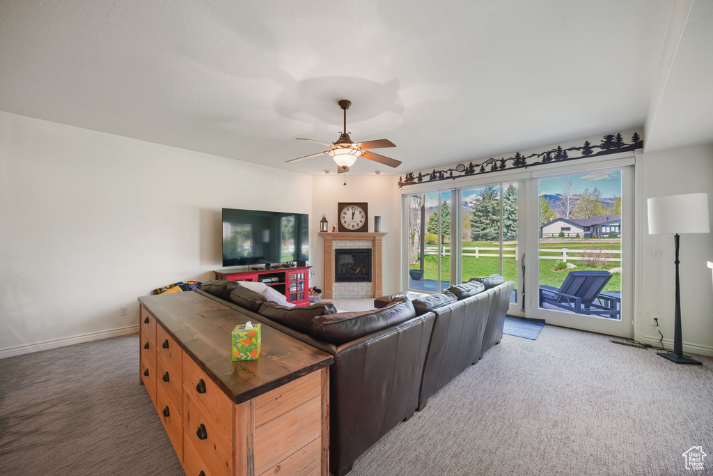 Living room featuring baseboards, ceiling fan, light carpet, and a tile fireplace