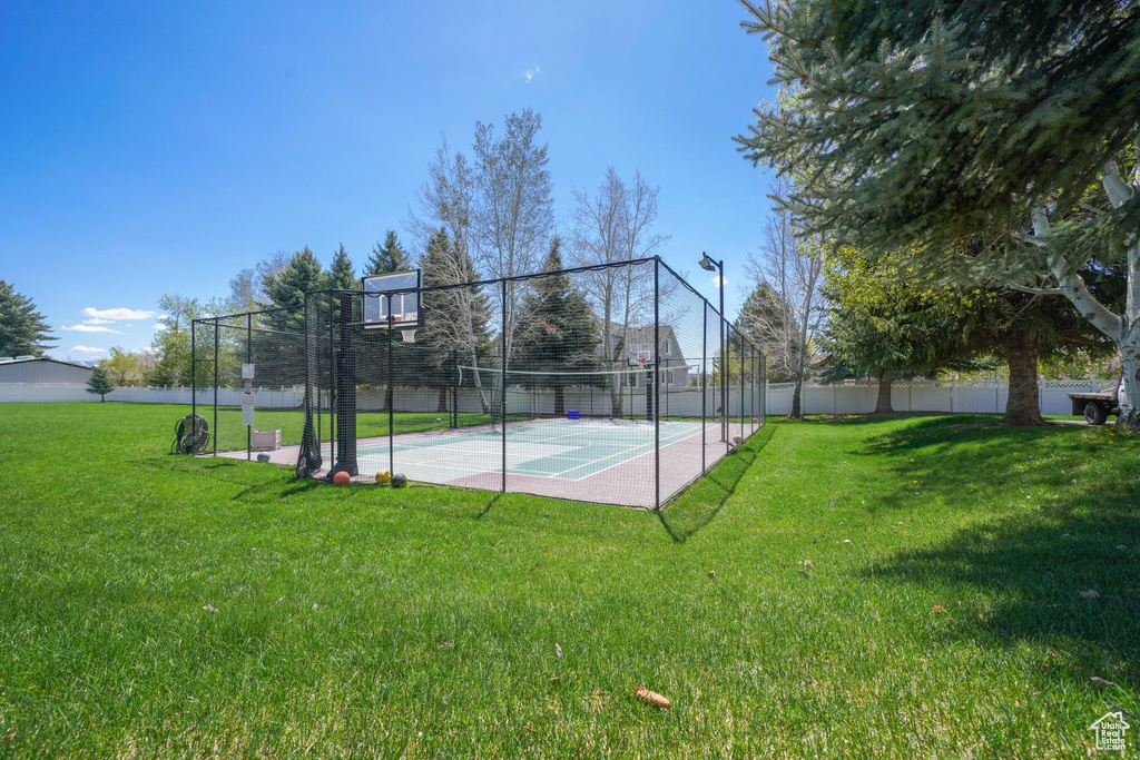 View of sport court featuring a lawn, community basketball court, and fence