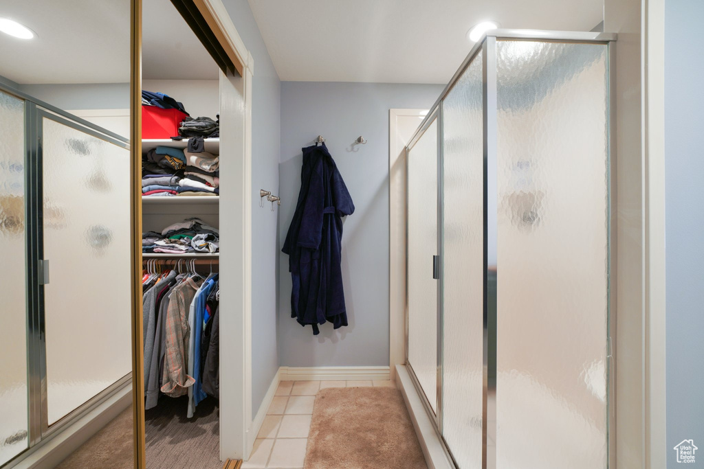 Bathroom with baseboards, tile patterned flooring, a shower stall, and a spacious closet