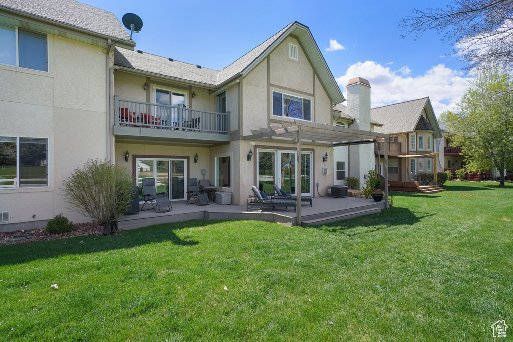 Back of property featuring a lawn, a pergola, a balcony, and stucco siding