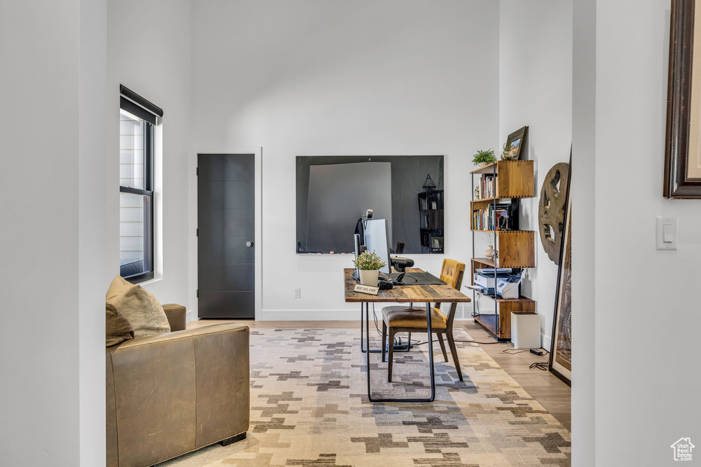 Office space featuring a high ceiling, light wood-style flooring, and baseboards