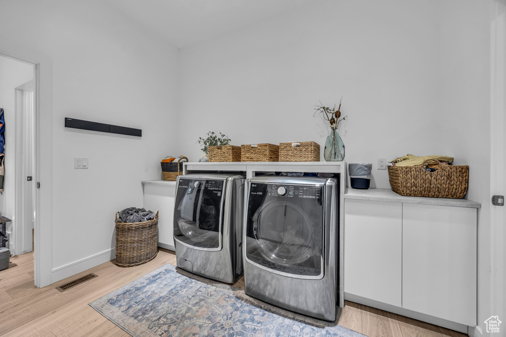 Laundry area featuring washer and dryer, light wood-style flooring, and baseboards
