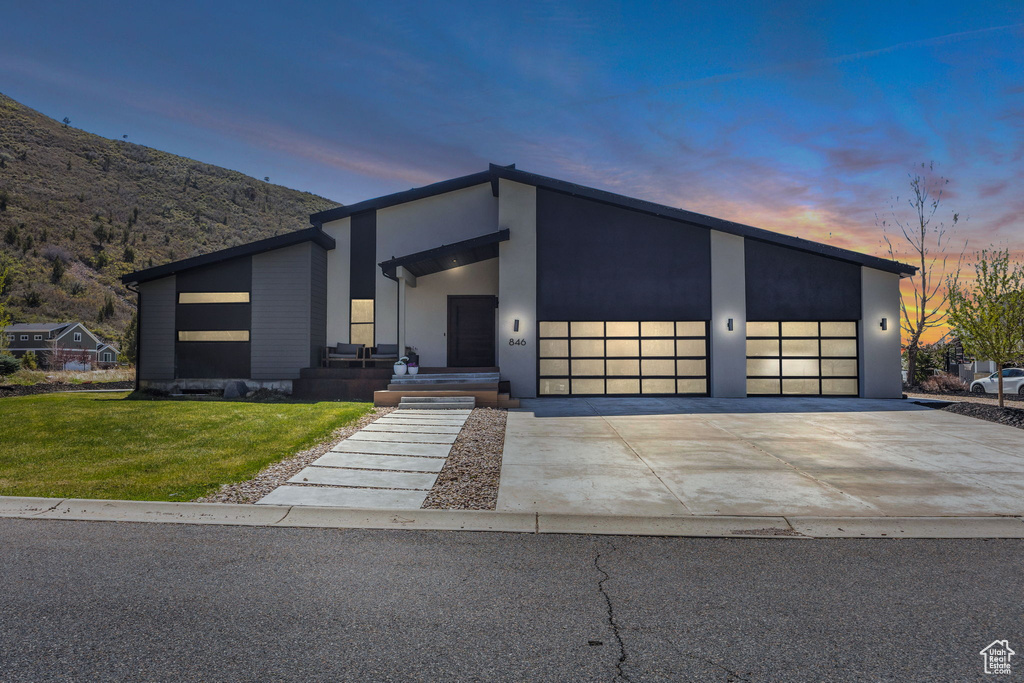 Contemporary house with a garage, driveway, a front yard, and stucco siding