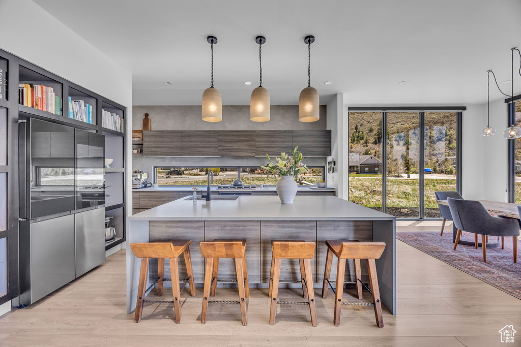 Kitchen with a sink, modern cabinets, a breakfast bar area, light wood finished floors, and a center island with sink
