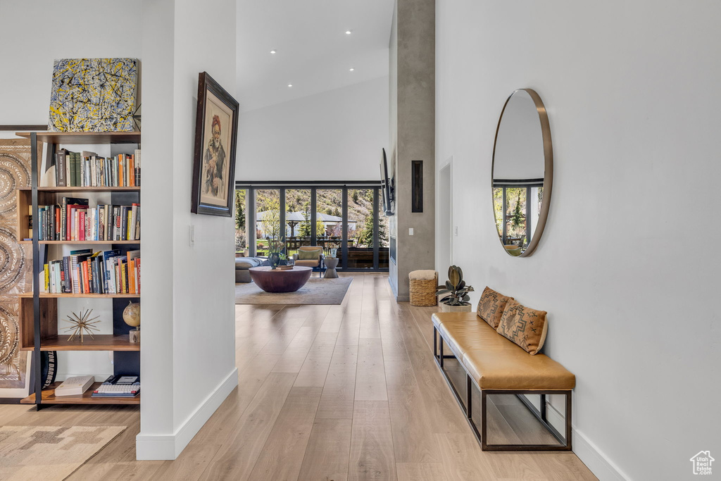 Hall with a high ceiling, wood finished floors, baseboards, and recessed lighting