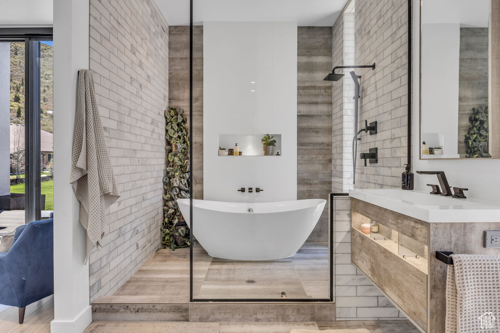 Bathroom featuring a walk in shower, a soaking tub, and vanity