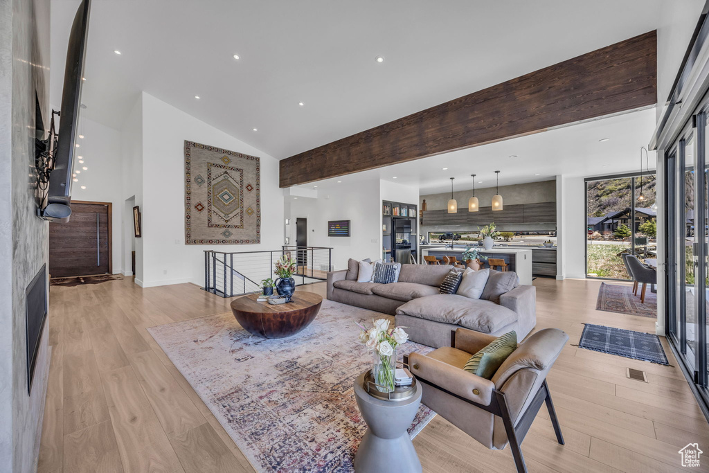 Living room with high vaulted ceiling, recessed lighting, light wood-type flooring, and baseboards