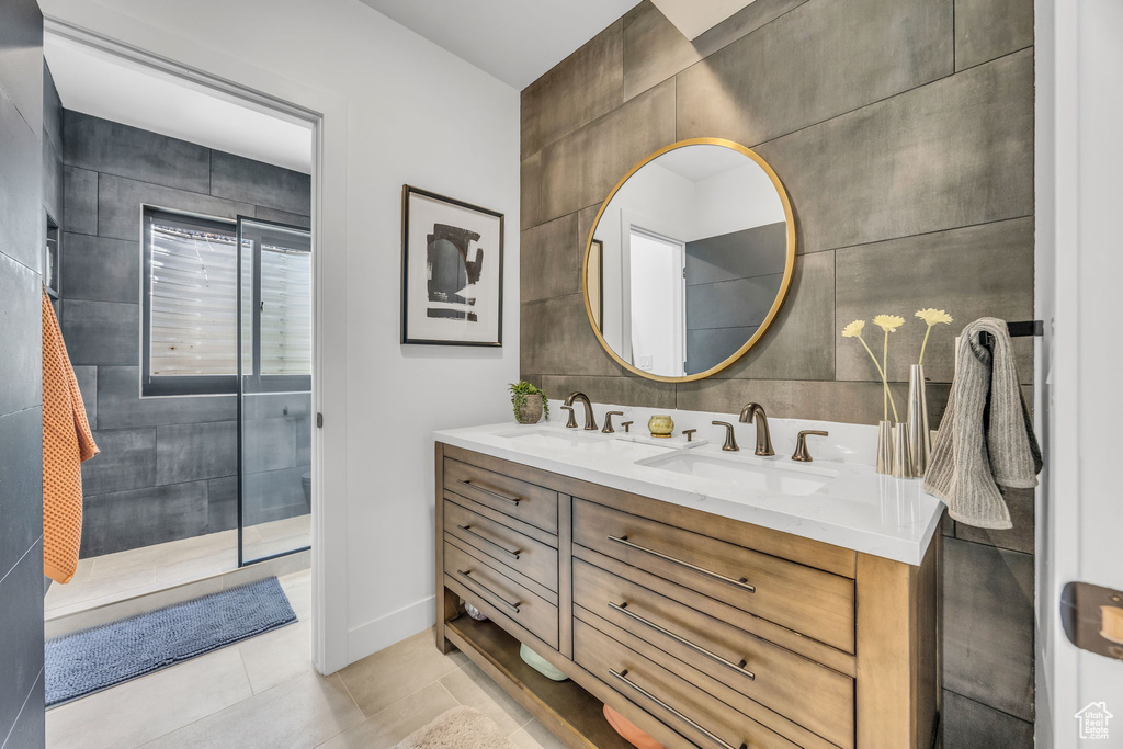 Bathroom with double vanity, tile patterned flooring, and tile walls