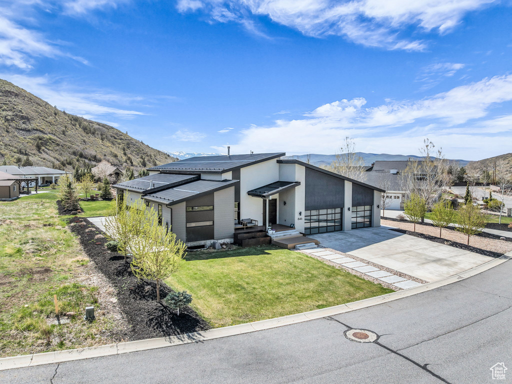 View of front facade featuring a mountain view, a front yard, driveway, and an attached garage