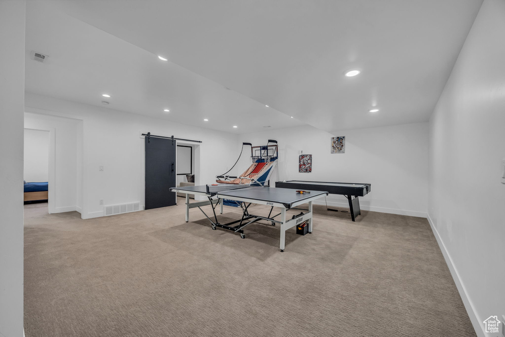 Recreation room featuring a barn door, light carpet, recessed lighting, and baseboards