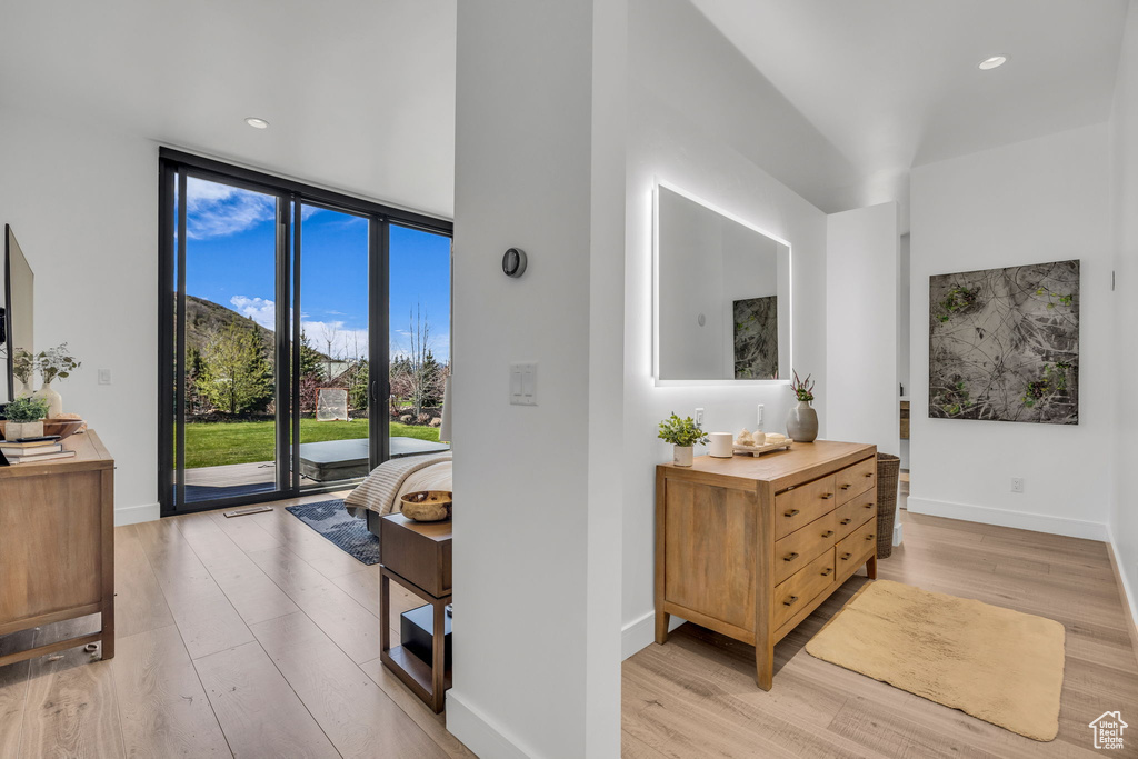 Hallway with light wood finished floors, baseboards, recessed lighting, and floor to ceiling windows