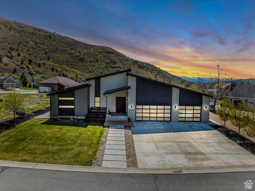 Modern home with a mountain view, a garage, a lawn, and driveway