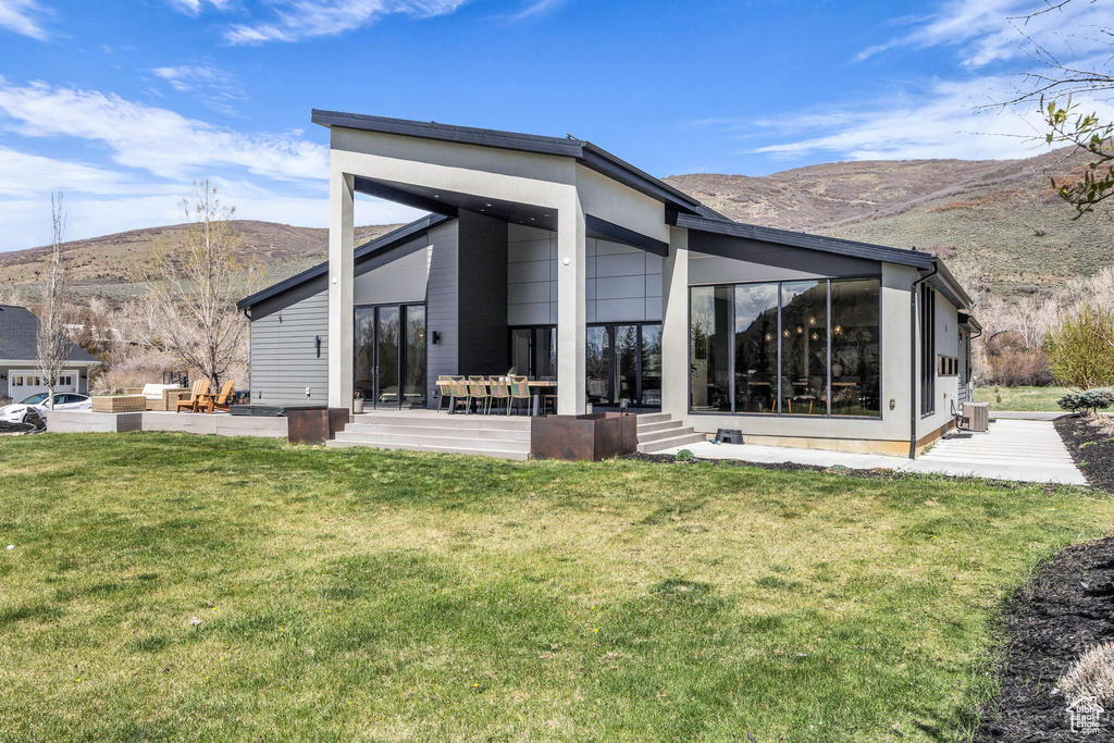 Back of house featuring a mountain view, a yard, and a patio