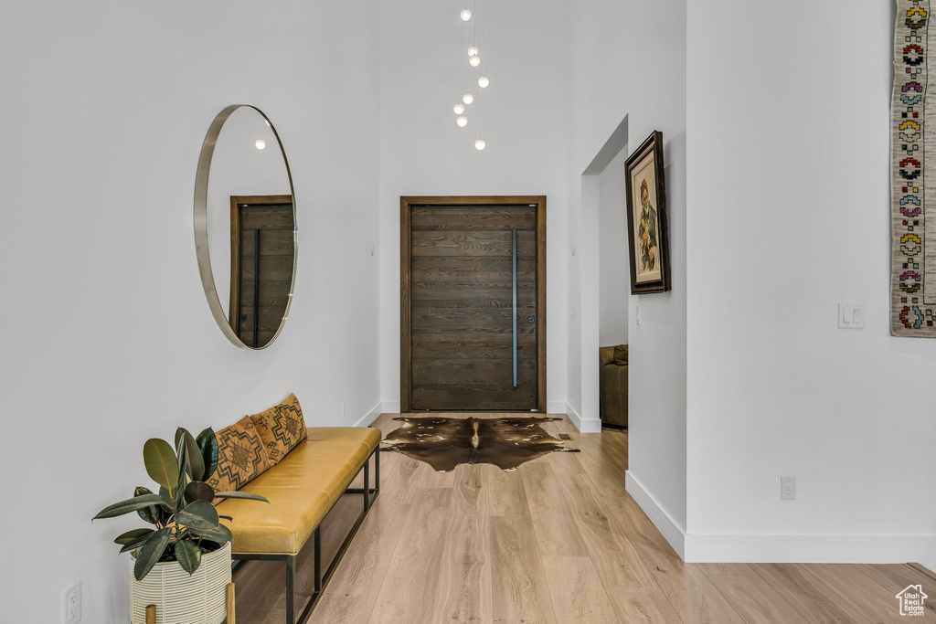 Entryway featuring light wood finished floors, baseboards, and a towering ceiling