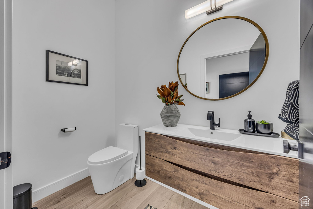 Bathroom with toilet, wood finished floors, vanity, and baseboards