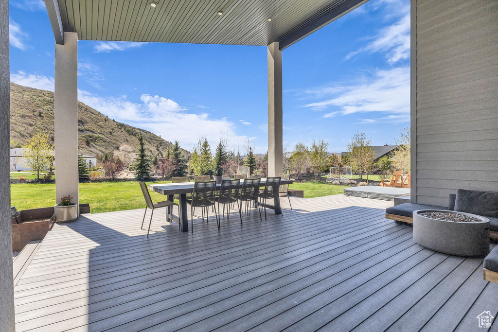 Wooden terrace featuring outdoor dining space, a yard, and a mountain view