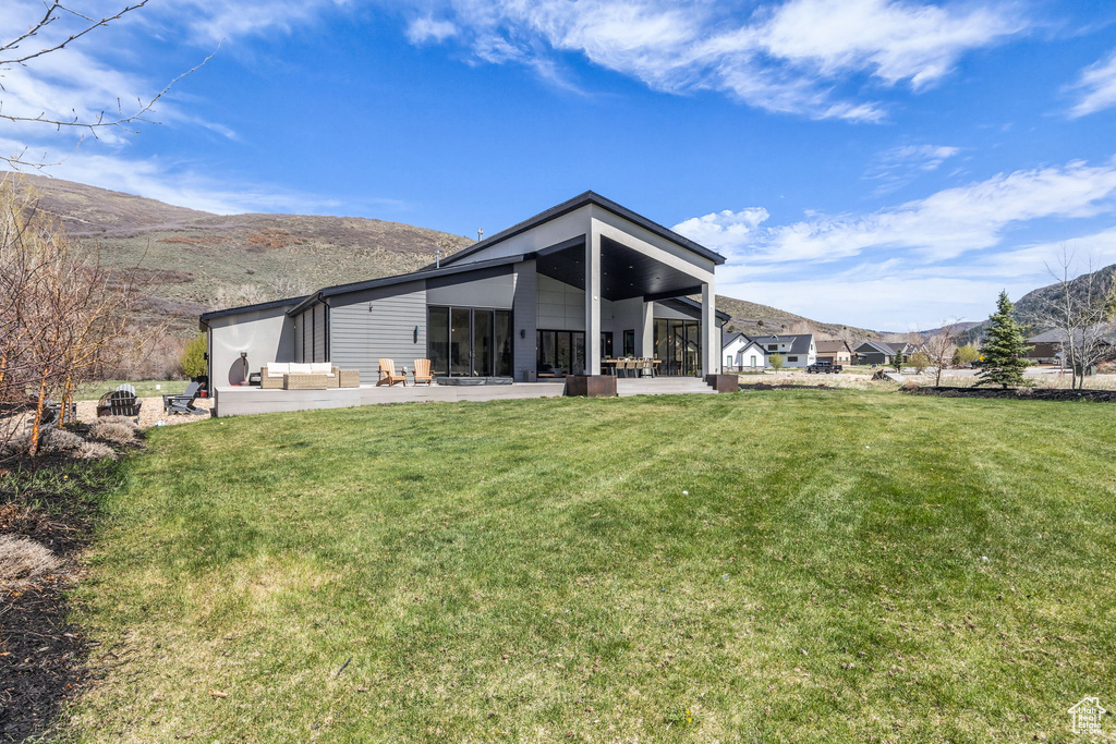 Rear view of property featuring a sunroom, a lawn, and a mountain view