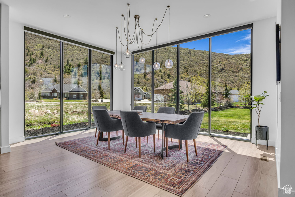 Dining room with floor to ceiling windows, healthy amount of natural light, wood finished floors, a chandelier, and a mountain view