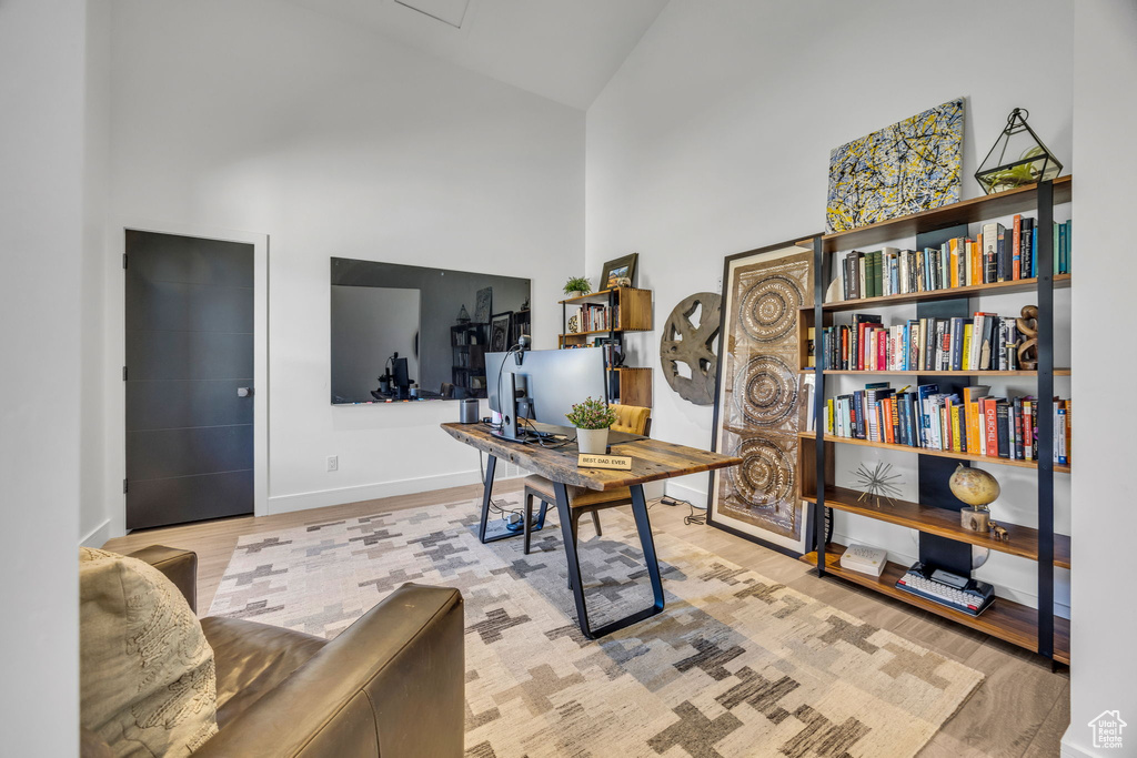 Home office with high vaulted ceiling, wood finished floors, and baseboards