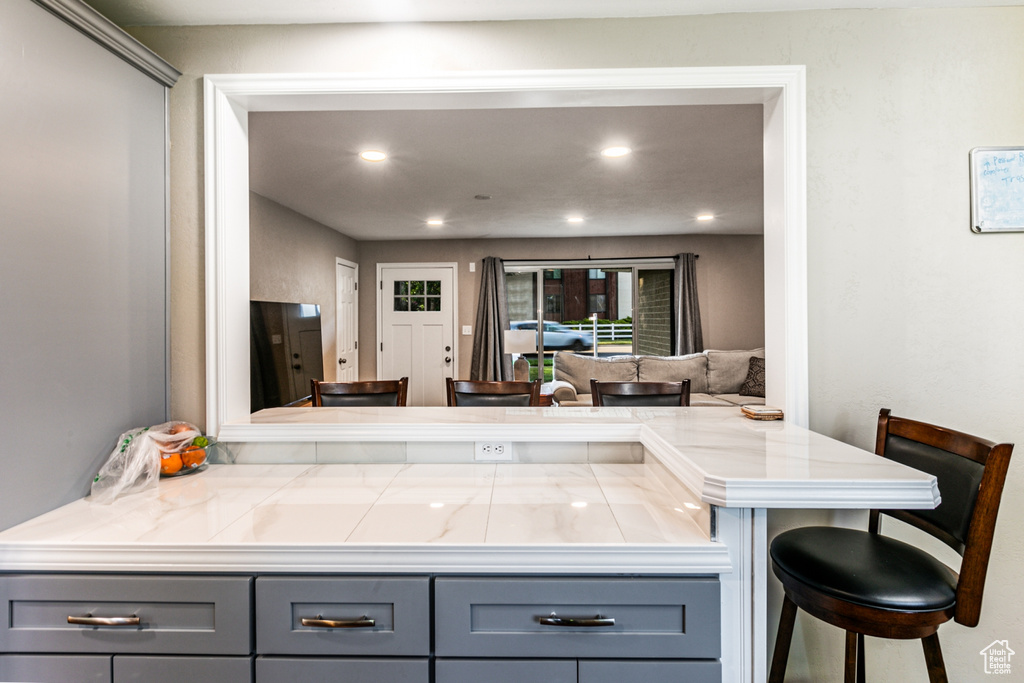 Kitchen featuring a peninsula, a kitchen breakfast bar, open floor plan, gray cabinets, and recessed lighting