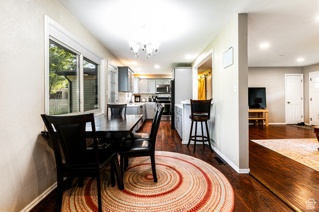 Dining room with a notable chandelier, recessed lighting, baseboards, visible vents, and dark wood-style floors