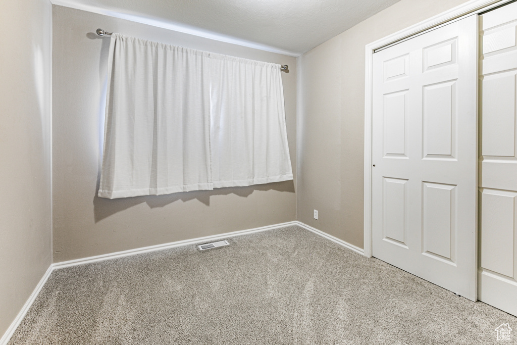 Unfurnished bedroom with visible vents, baseboards, and carpet floors