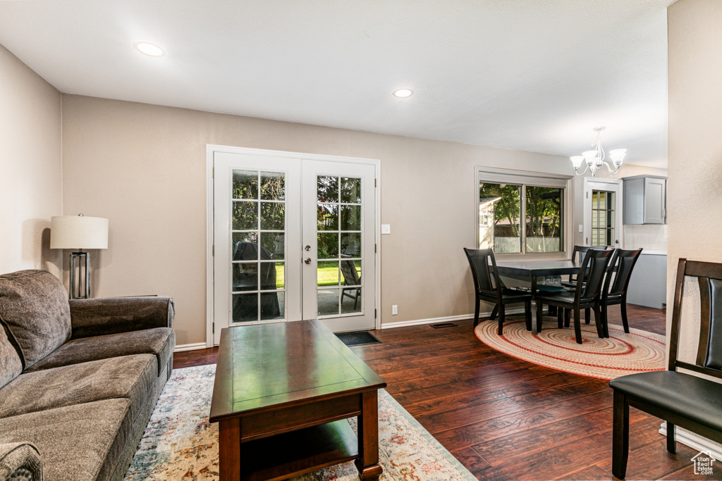 Living room with french doors, recessed lighting, an inviting chandelier, dark wood-style flooring, and baseboards