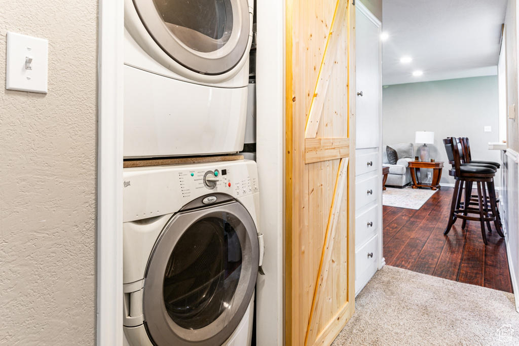 Laundry room featuring stacked washing maching and dryer, a textured wall, laundry area, and recessed lighting