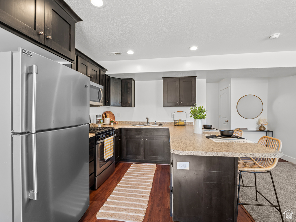 Kitchen with a peninsula, a sink, stainless steel appliances, light countertops, and recessed lighting