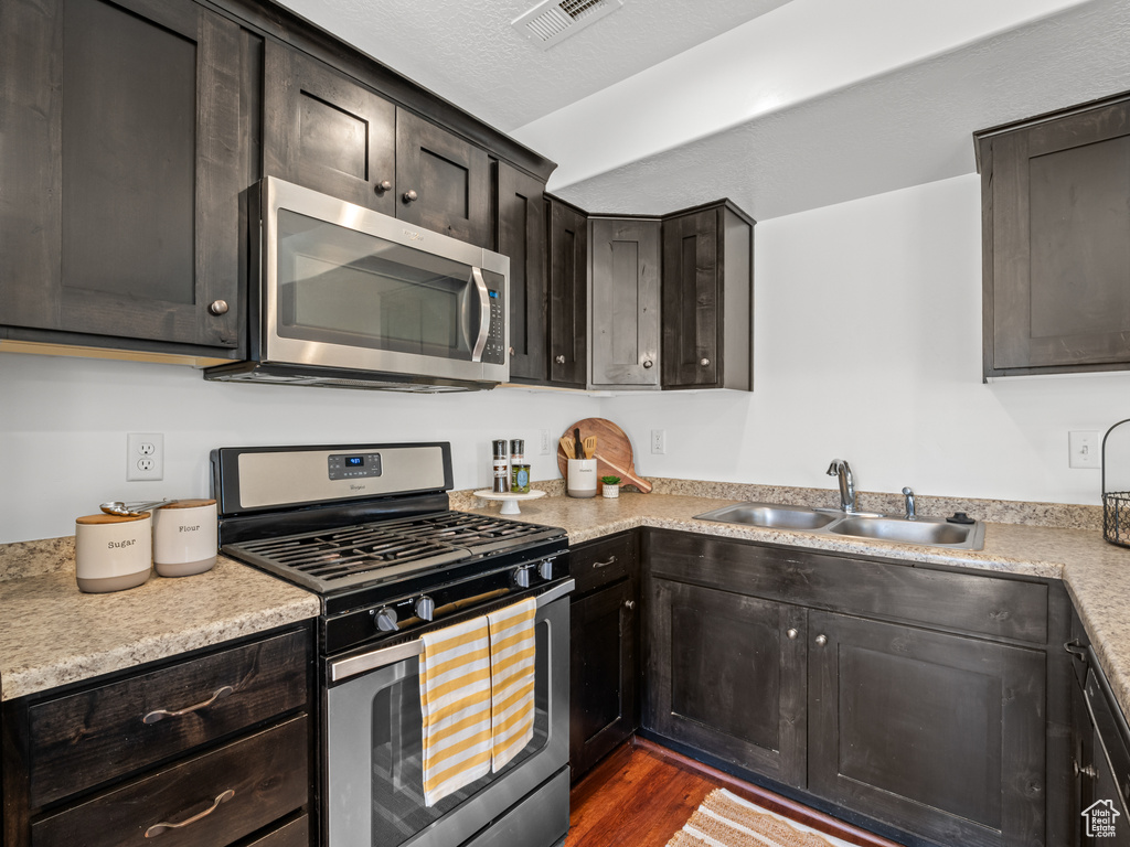 Kitchen featuring light countertops, appliances with stainless steel finishes, visible vents, and a sink