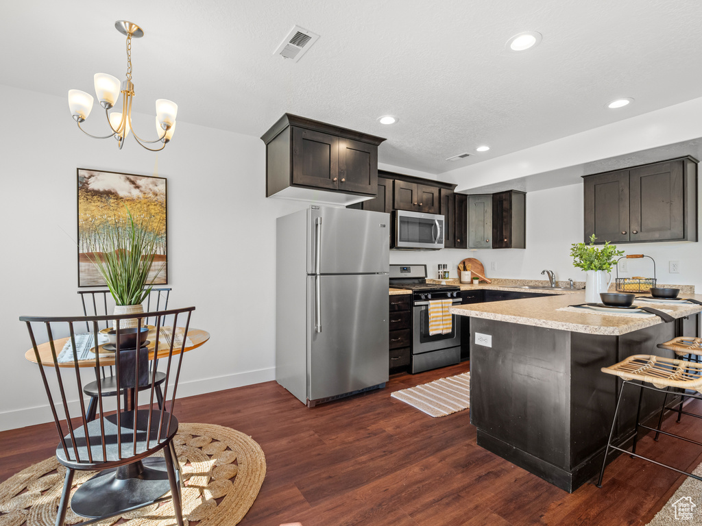 Kitchen with recessed lighting, a sink, light countertops, appliances with stainless steel finishes, and dark wood-style floors