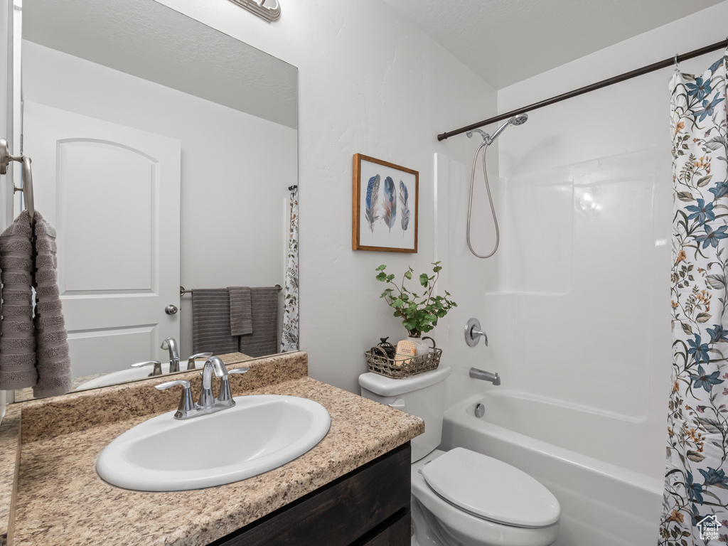 Bathroom featuring toilet, shower / tub combo with curtain, and vanity