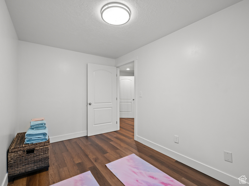 Interior space featuring dark wood finished floors, baseboards, and a textured ceiling