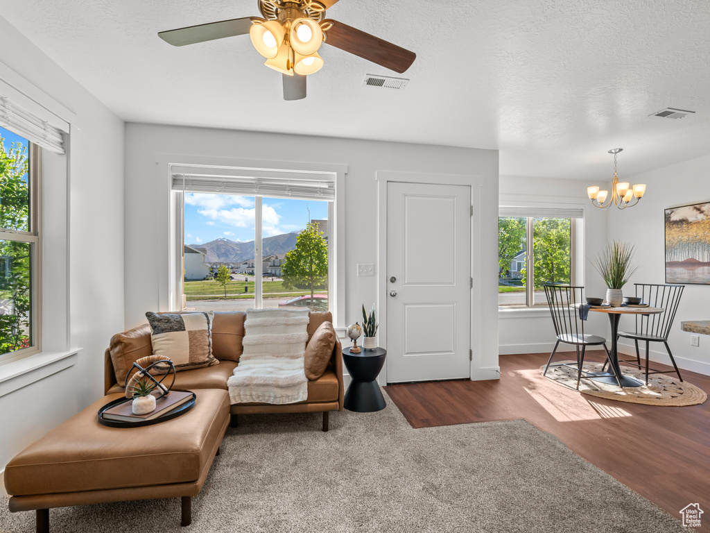 Living area with a mountain view, ceiling fan with notable chandelier, visible vents, and wood finished floors