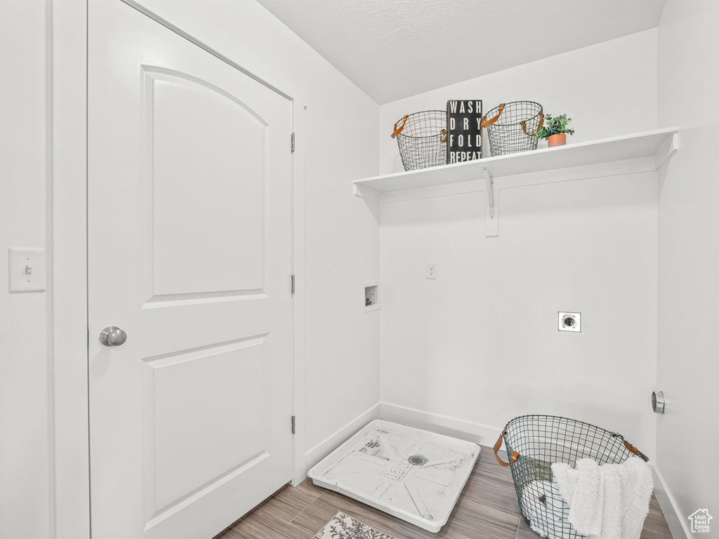 Laundry room with wood finished floors, laundry area, hookup for an electric dryer, hookup for a washing machine, and baseboards