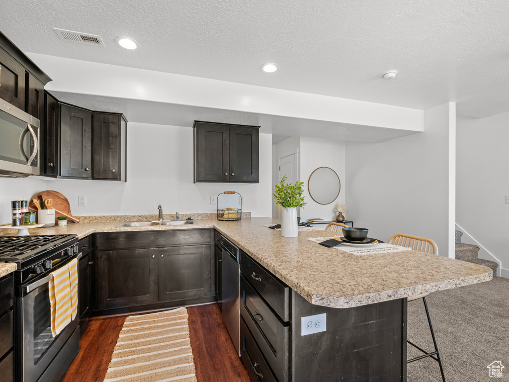 Kitchen featuring visible vents, a sink, a peninsula, light countertops, and appliances with stainless steel finishes